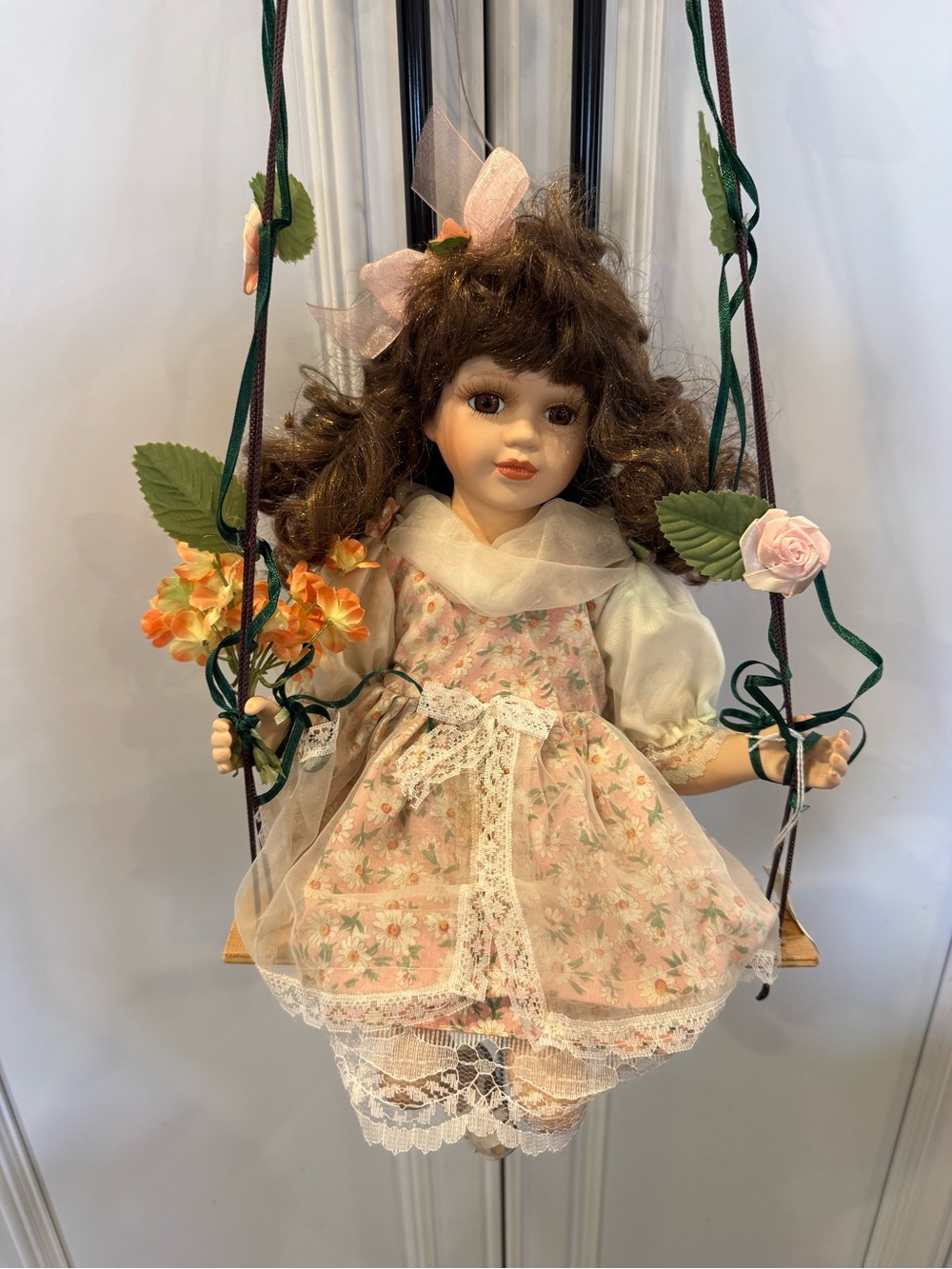 Vintage Porcelain Doll in Pink Floral Dress with Cream Blouse hanging on swing